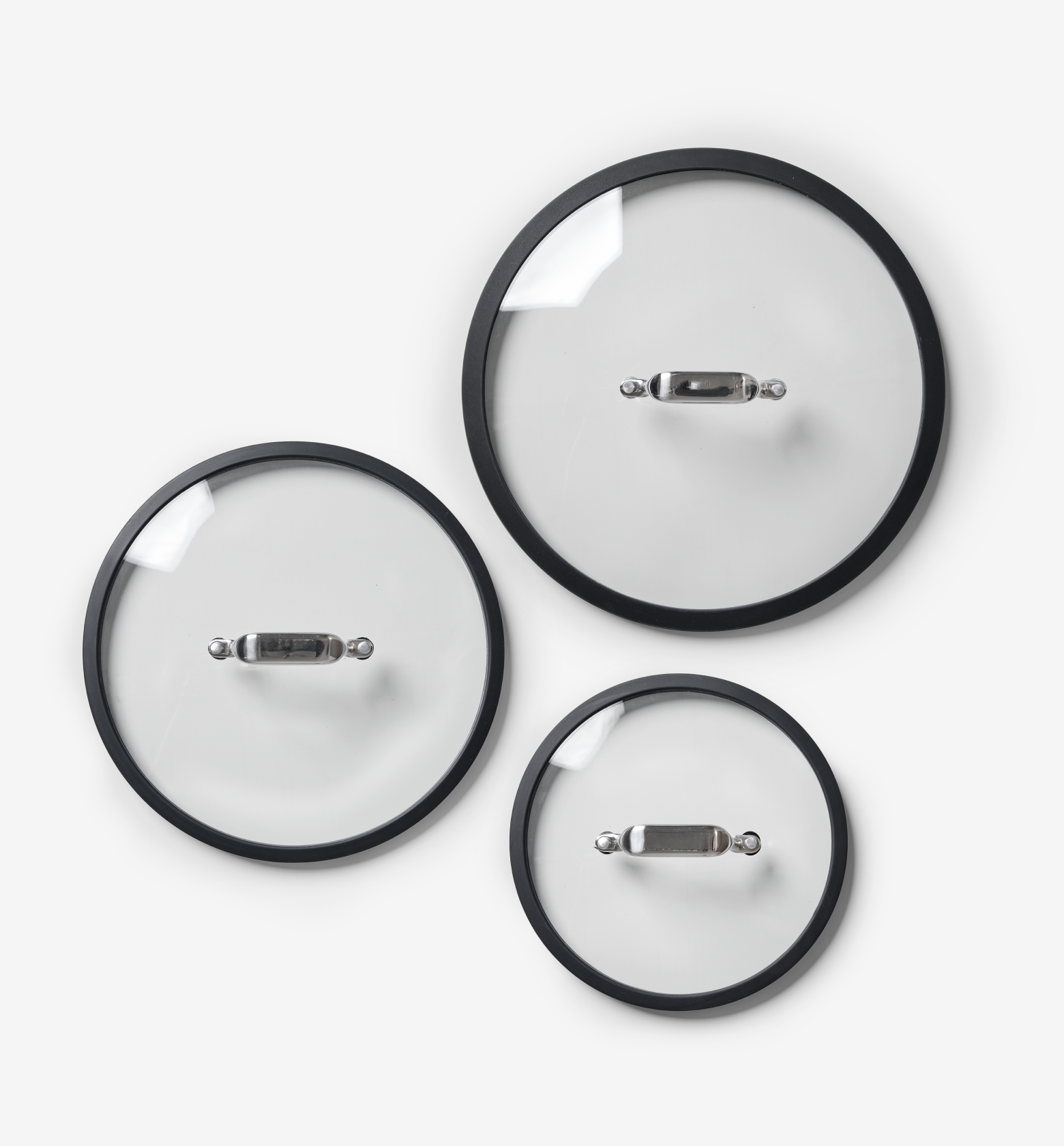 Set of three glass pot lids with black silicone rims and stainless steel handles in small medium large sizes