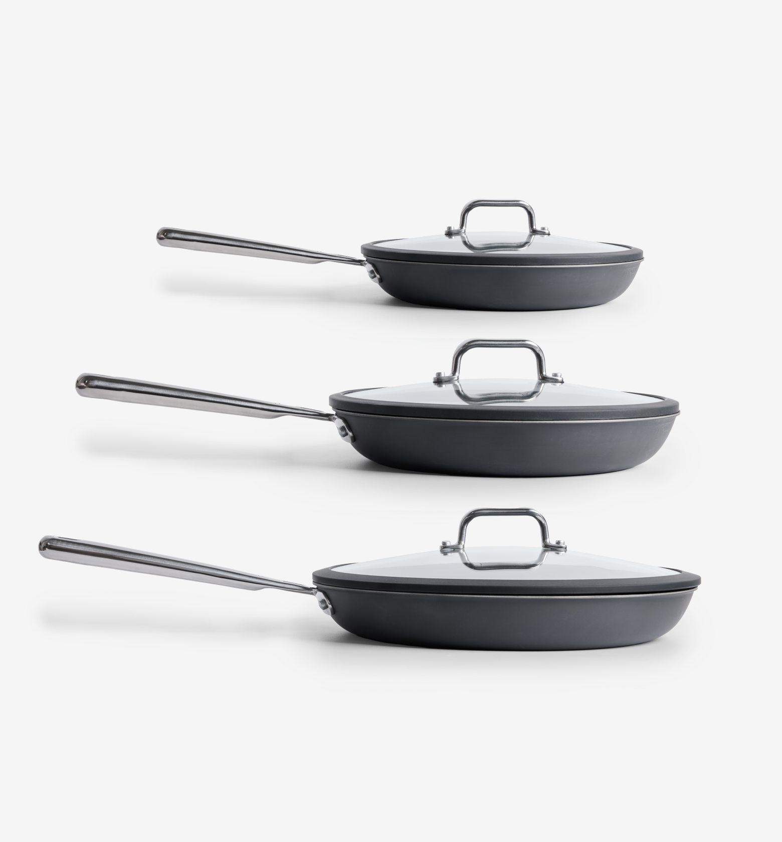 Set of three hard-anodized nonstick frying pans with glass lids and stainless steel handles in graduated sizes